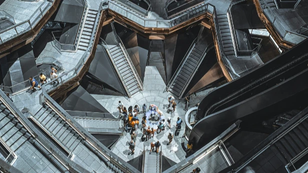 Intérieur du Vessel à New York, des gens au centre du bâtiment, d'autres montent et descendent les différents escaliers